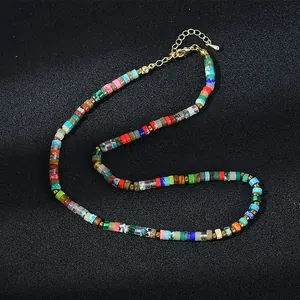 Collier de perles cylindriques colorées avec fermoir mousqueton doré sur fond noir
