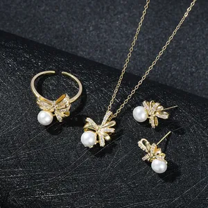 Dettaglio di un elegante set di gioielli con fiocchi dorati e perle su un supporto