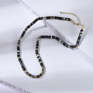 Détail d'un collier de perles cylindriques en marbre avec intercalaires dorés et fermoir