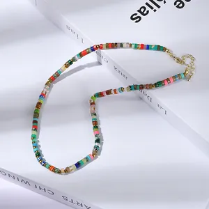 Détail d'un collier de perles marbrées colorées avec fermoir doré sur un livre