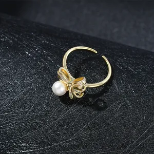 Dettaglio dell'anello regolabile dorato con fiocco di cristalli e una perla bianca