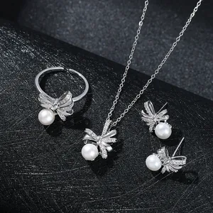 Set di gioielli in argento con fiocchi, perle e cristalli su sfondo nero di classe