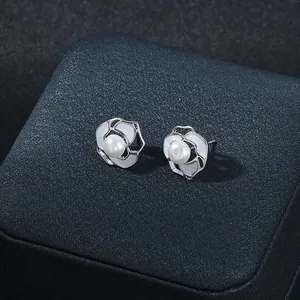 Dettaglio macro di orecchini a camelia in argento con perla su scatola portagioie