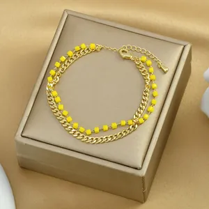Dettaglio di un bracciale a doppio strato dorato con perline gialle su raso