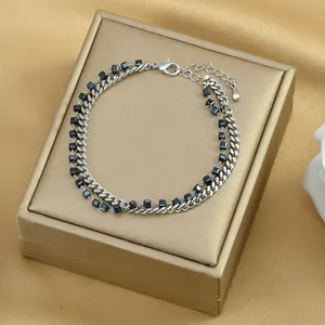 Dettaglio del bracciale a catena argento a doppio strato con perline nere su scatola oro