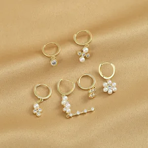 Detailansicht von goldenen Ohrring-Sets mit Perlenanhängern und Zirkoniasteinen