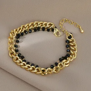 Dettaglio del bracciale a doppio strato con catena barbazzale dorata, perline nere e chiusura
