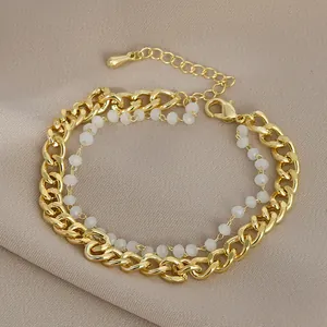 Dettaglio del bracciale a doppia catena dorata con perle bianche su seta morbida