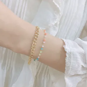 Bracciale a doppio strato con catena dorata e perle colorate indossato sul polso