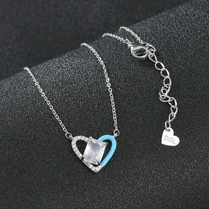 Collier pendentif cœur en émail bleu et zircon avec chaîne argentée sur tissu noir chic