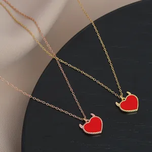 Detailed view of red heart pendants with devil horns on gold and rose gold necklaces
