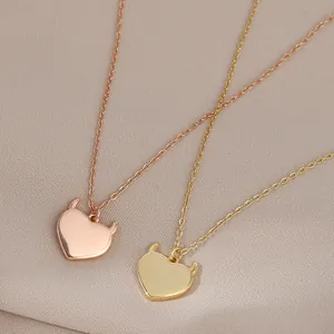 Polished gold and rose gold devil heart pendant necklaces on beige textured fabric