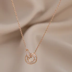 Collana in oro rosa con doppi anelli intrecciati e zirconi su sfondo di seta beige