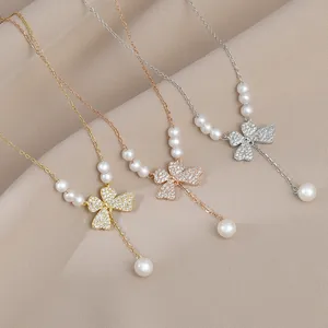 Detail of bow-shaped necklaces in gold and silver with inlaid zircons and pearls