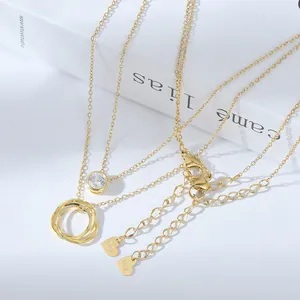 Primo piano di collane placcate oro con anelli intrecciati e pendente in zircone sui libri