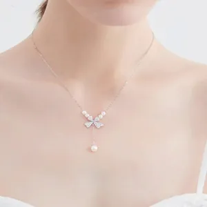 Detail of gold-plated necklace featuring a diamond bow pendant and five white pearls