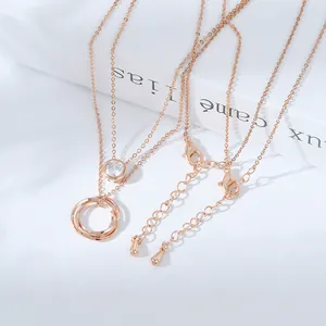 Collana a strati in oro rosa con ciondolo a triplo anello e zircone su sfondo bianco