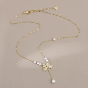 Detail of gold bow necklace with micro-set zircon butterfly and elegant pearl tassels