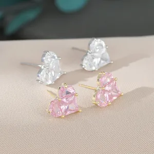 Détail macro de boucles d'oreilles cœur en cristal rose et blanc avec serti à griffes