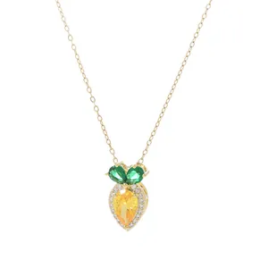 Gold plated necklace with carrot pendant featuring yellow stones and green leaf accents