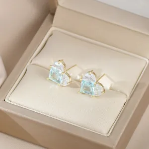 Détail macro de boucles d'oreilles cœur avec pierre bleue et monture dorée élégante