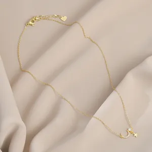 Detail van vergulde ketting met maan en ster hanger en zirkoon op zijden stof