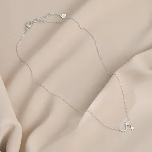 Detailopname van zilveren maan- en sterhanger ketting op beige getextureerde stof