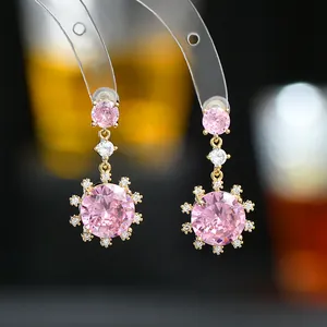 Détail macro de boucles d'oreilles flocon en zircon rose avec placage or et halo