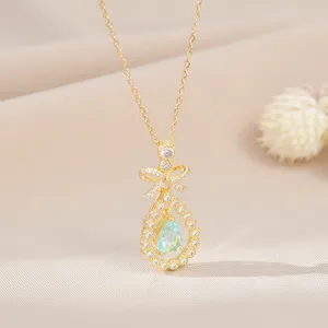 Gros plan d'un pendentif nœud doré avec pierre bleue en goutte et zircons blancs