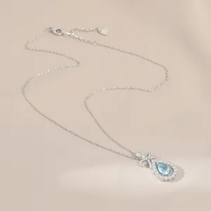 Gros plan du pendentif nœud argenté avec pierre bleue goutte et zircons sertis