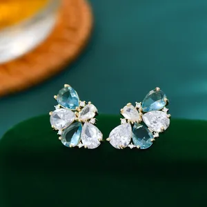 Detail van bloemvormige oorbellen met blauwe en witte zirkonia op verguld metaal