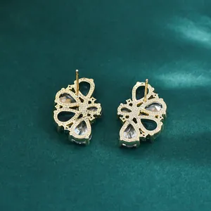 Elegante gouden vlinder oorbellen met groene stenen en zirkoon op donkergroene achtergrond