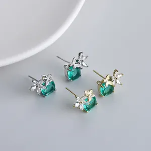 Dettaglio degli orecchini a farfalla con pietre verde smeraldo in oro e argento lucido