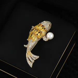 Elegant gold-tone koi fish brooch with yellow gems, white diamonds, and a round pearl