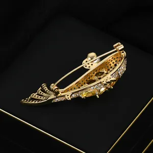 Golden koi fish brooch with glittering crystals and a white pearl on a jewelry box