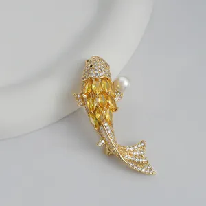 Macro detail of gold koi fish brooch with yellow rhinestones and white pearl accent