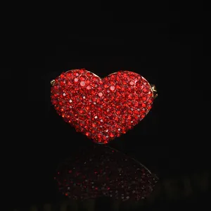 Sparkling red heart brooch with crystals on a black reflective background