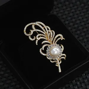 Élégante broche plume dorée avec pavé de diamants et perle blanche dans son écrin noir