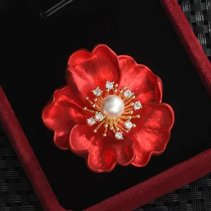 Macro d'une broche pivoine rouge avec pétales brossés, perle centrale et accents dorés