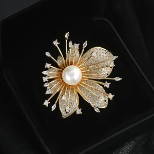 Elegant gold flower brooch with white pearl and sparkling zircon crystals on black velvet