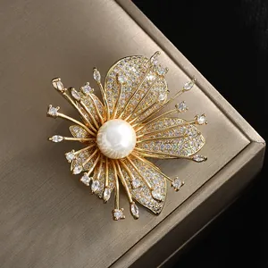 Elegant gold flower brooch with white pearl center and zircon crystals on black background
