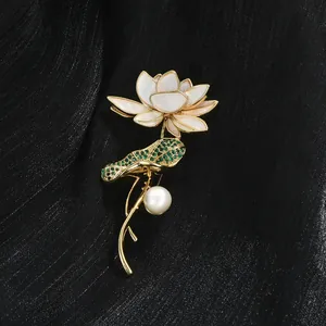 Détail d'une broche lotus élégante avec cristaux verts et grande perle sur tissu