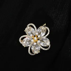 Macro shot of gold-plated five-petal flower brooch with sparkling zircon on black fabric