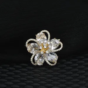 Elegant gold plated five-petal flower brooch with sparkling cubic zirconia on black fabric
