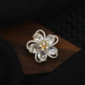 Elegant gold plated flower brooch with sparkling zircon petals on a dark luxury background