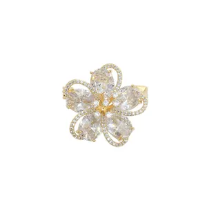 Golden flower brooch with five petals and shimmering cubic zirconia stones on white background