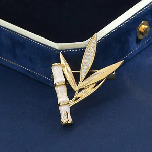 Détail de la broche bambou avec pierres œil de chat blanches et feuilles dorées