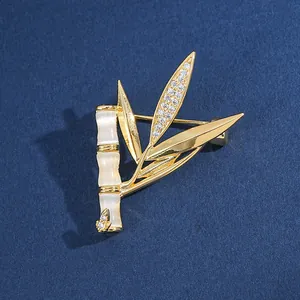 Vue détaillée de la broche bambou dorée avec pierres œil de chat et feuilles en zircon