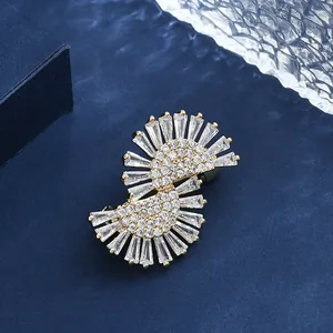 Elegant S-shaped gold brooch with baguette-cut zircon stones on a navy velvet background
