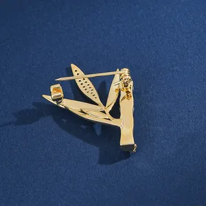 Broche feuille de bambou dorée avec zircon et opale sur fond sombre et texturé